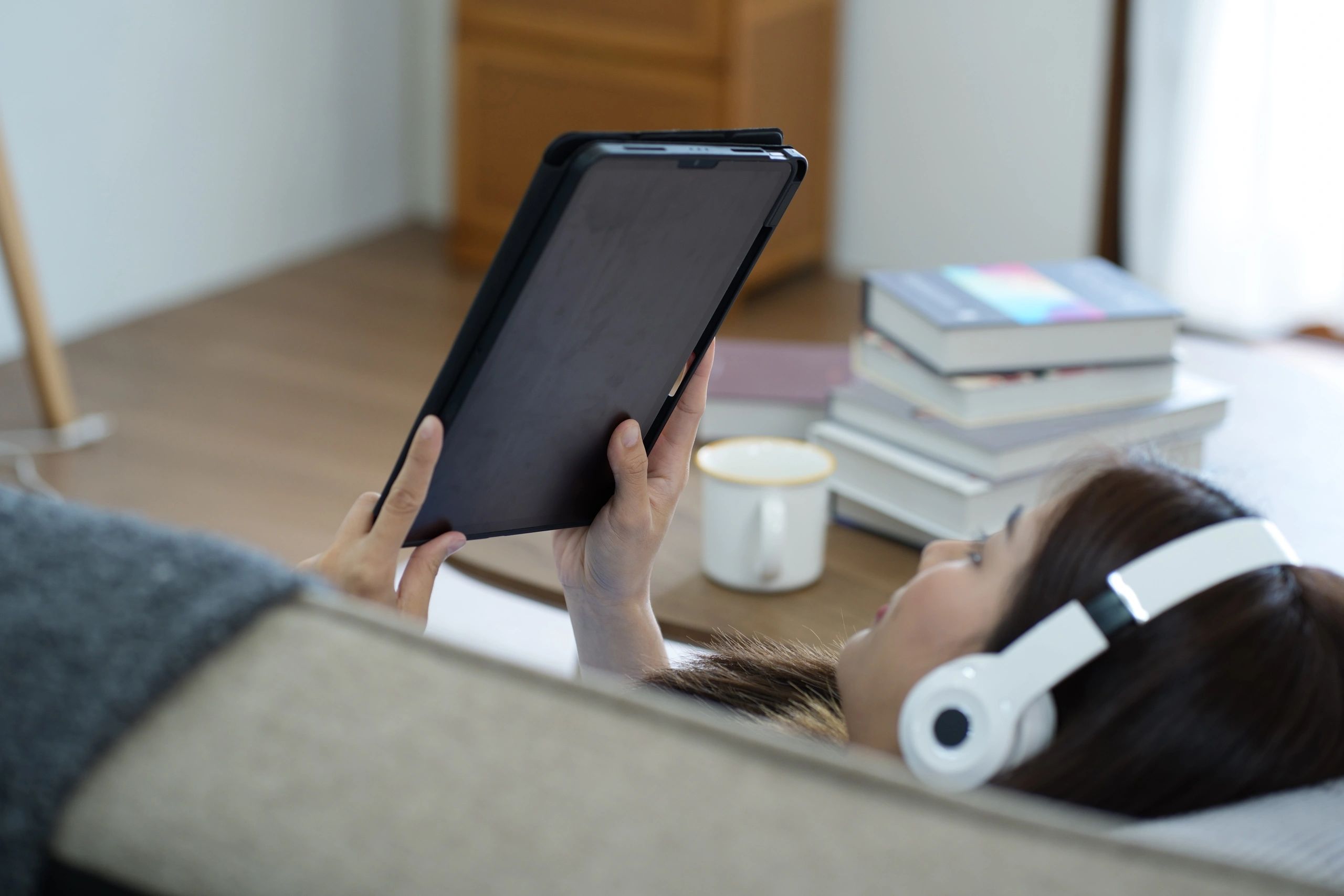 Young adult reading on a tablet on a sofa